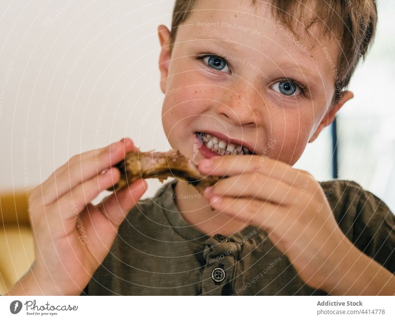 Hungriges Kind isst Schweinerippchen beim Mittagessen Schweinefleisch Rippe heimwärts Lebensmittel Junge appetitlich niedlich Mahlzeit bezaubernd genießen