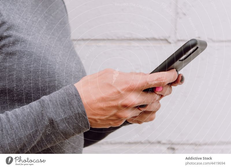 Anonyme Frau in Freizeitkleidung mit Smartphone benutzend Straße Zeitgenosse hell Apparatur Gerät jung Telefon Surfen Internet Mobile Browsen Wand modern froh