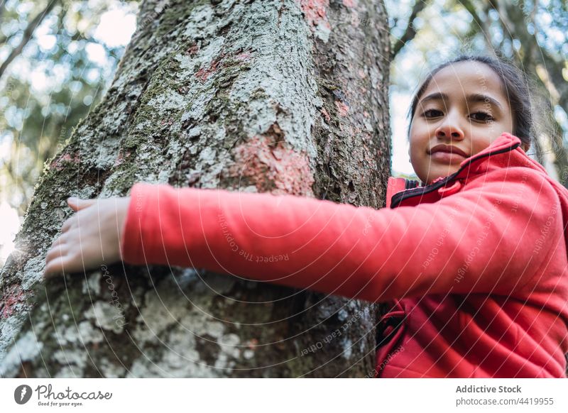 Ethnisches Mädchen an altem Baumstamm im Wald Kofferraum Rinde Natur Umwelt Ökologie bewahren Porträt Flechten Wälder Kind konservieren behüten Kindheit