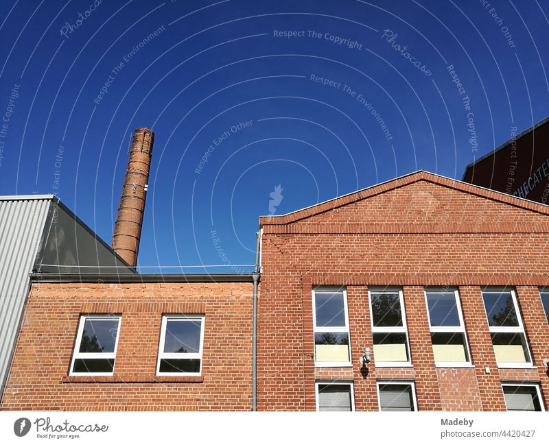 Rotbraune sanierte Klinkerfassade mit hohem Schornstein vor blauem Himmel bei Sonnenschein in Lemgo bei Detmold in Ostwestfalen-Lippe Fabrik Schlot Fabrikschlot