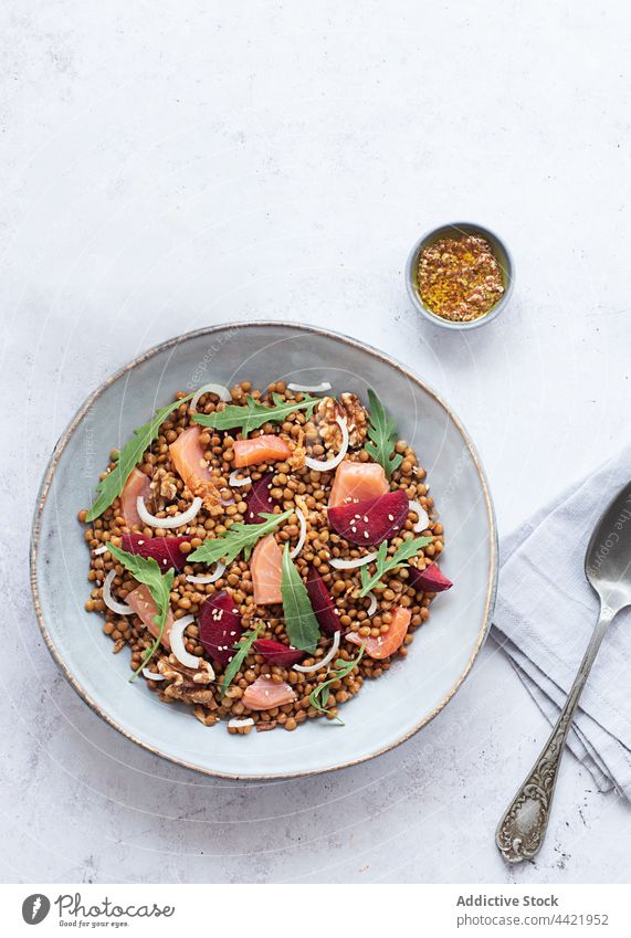 Nahaufnahme eines Lachs- und Linsensalats von oben Draufsicht Essen Draufsicht Tabelle Tischdecke Weinflasche Weinglas Senf Pflaume Räucherlachs-Salat Rucola