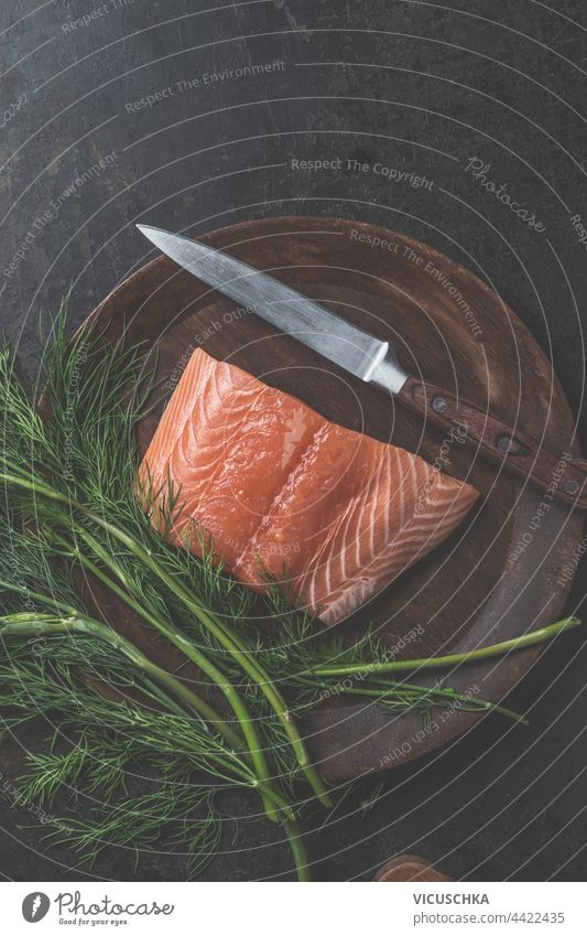 Portion rohes Lachsfilet mit einem Bund Dill und einem Messer auf einem Holzteller. Ansicht von oben Filet Haufen hölzern Teller Draufsicht Hintergrund