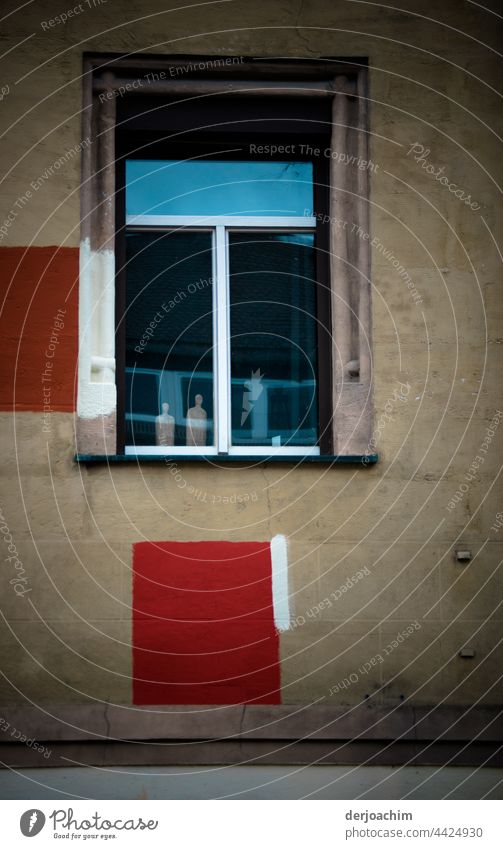 Die Fenster sind  geschlossen. Zwei kleine Figuren stehen hinter der Scheibe. Neben und unter dem Fenster sind in Rot zwei Markierungen angebracht die mit  weißen Streifen versehen sind.