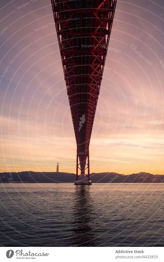 Vertäuungsmasten unter der Brücke bei Sonnenuntergang Mast Maure Fluss Ufer Himmel wolkig Wasser Konstruktion Lissabon Portugal 25 de abril brücke Tagus-Fluss