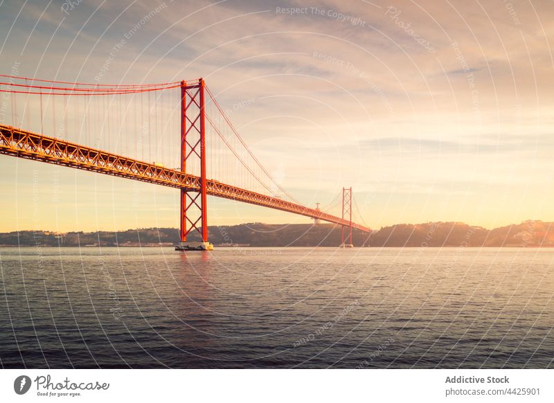 Moderne Brücke über den Fluss bei Sonnenuntergang Ufer Himmel wolkig Abend modern verbinden Denkmal Lissabon Portugal Almada 25 de abril brücke