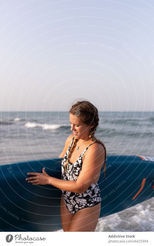 Frau mit Paddleboard am Meer Zusatzplatine SUP Paddelbrett Surfer MEER Sommer Badeanzug Surfbrett Ufer Wasser stehen Urlaub Badebekleidung Holzplatte genießen