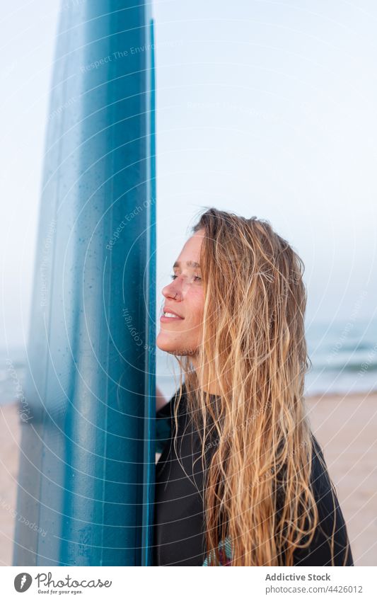 Surfer mit Paddleboard am Strand Frau Paddelbrett Zusatzplatine SUP Meeresufer Seeküste Sommer Surfbrett Ufer Holzplatte Sand Urlaub Erholung Küste stehen blau