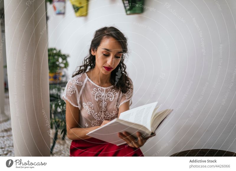 Ethnische Frau liest ein Buch im Innenhof lesen patio Etage Stil Inhalt Roman interessant Kälte ethnisch Belletristik Leseratte Fokus Wissen Lehrbuch Wochenende