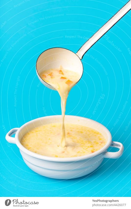 Griechische Suppe in einer weißen Emailleschale. Suppe aus der Schöpfkelle gießen avgolemono Hintergrund blau Schalen & Schüsseln Hähnchen Hühnersuppe