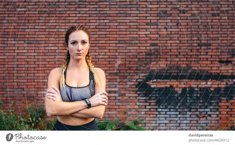 Sportlerin mit verschränkten Armen posiert verschränkte Arme Backsteinwand schauende Kamera Textfreiraum Taille hoch Ermächtigung aktiv Wand ernst Boxerflechten