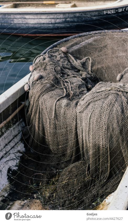 ein altes Fischernetz liegt in einem kleinen Fischerboot Boot grau braun Fischen Außenaufnahme Fischereiwirtschaft Netz netzartig Meer Tag Fischereihafen