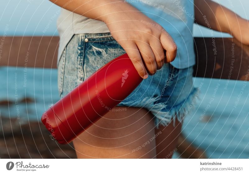 Junge Frau hält rote Wasserflasche in den Händen Flasche T-Shirt Attrappe Metall Stehen Beteiligung junger Erwachsener blau abschließen gesichtslos