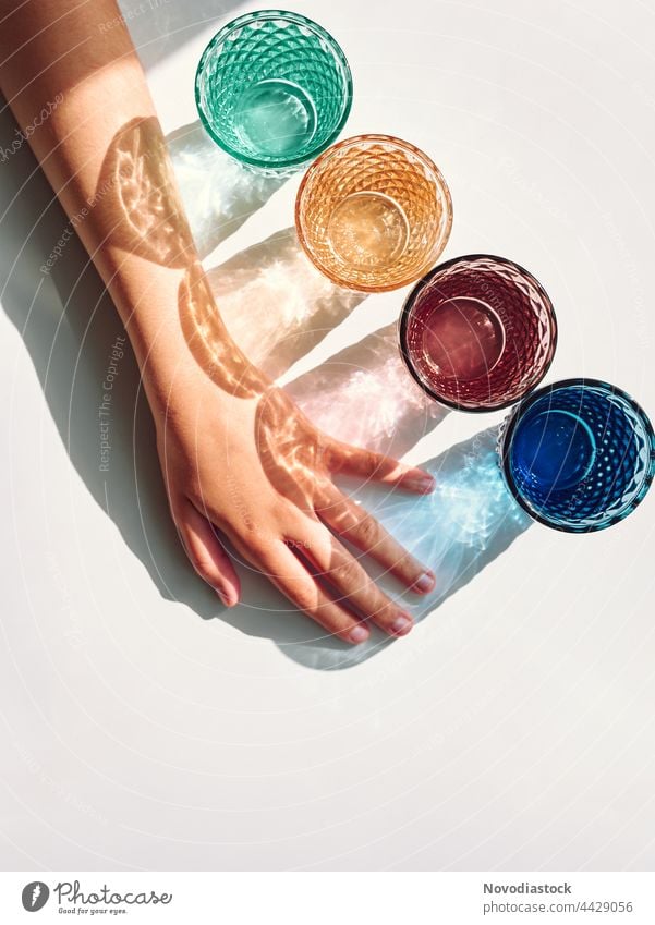 Bunte Brille mit Schatten und einem Mädchenarm isoliert auf einem weißen Hintergrund Glas trinken Getränk Farbfoto Innenaufnahme Trinkwasser Tag Wasser