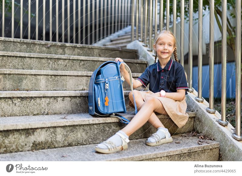 Schulmädchen zurück zur Schule nach den Sommerferien. Kind in Uniform mit Rucksack am frühen Morgen im Freien. Bildung öffentliche Schule Schulkind Schüler