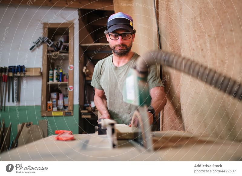 Fokussierter Tischler schneidet Holz an einer Sägemaschine im Arbeitsraum Zimmerer geschnitten Schiffsplanken Maschine präzise Werkstatt Mann Kunsthandwerker