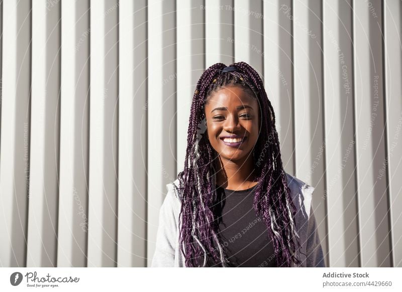 Fröhliche schwarze Frau mit Afro-Haar Glück Afro-Look Geflecht Lächeln Spaß haben heiter Freude Stil modern urban positiv ethnisch Afroamerikaner gefärbtes Haar