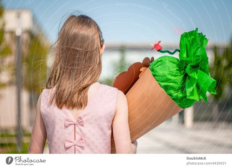 Ein Mädchen steht vor der Schule mit einer Schultüte auf dem Arm Zuckertüte Einschulung Kind Farbfoto Kindheit Bildung lernen Schulkind Schüler schülerin Mensch