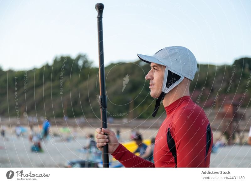 Mann mit Paddel und Brett vor dem Surfen Paddelbrett Zusatzplatine Surfer Meeresufer Neoprenanzug Strand männlich Surfbrett Sand Sport Brandung MEER Seeküste