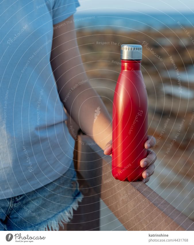 Junge Frau hält rote Wasserflasche in den Händen Flasche T-Shirt Attrappe Metall Stehen Beteiligung junger Erwachsener blau abschließen gesichtslos