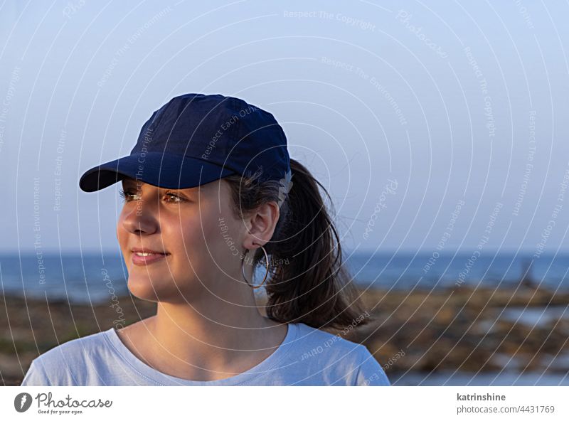 Teenager-Mädchen mit dunkelblauer Baseballmütze bei Sonnenuntergang im Freien Jugendlicher Kaukasier Attrappe visier zur Seite schauen Kopf tragend Kindheit