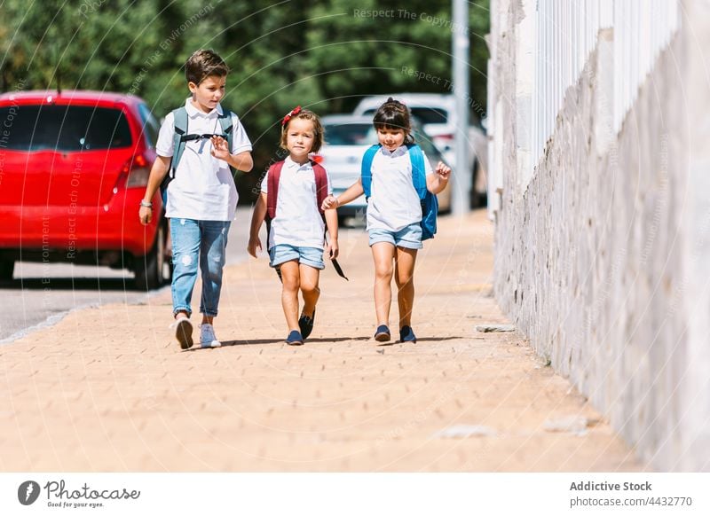 Schulkinder unterhalten sich beim Gehen auf dem Bürgersteig in der Stadt Jeansstoff Gespräch Freundschaft zurück zur Schule Kindheit sorgenfrei schlendern