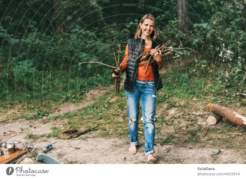 Ein Touristenmädchen sammelt in der Natur Brennholz für ein Feuer. Eine Frau in Großaufnahme. Das Konzept von Reisen und Abenteuer Camping Freudenfeuer reisen