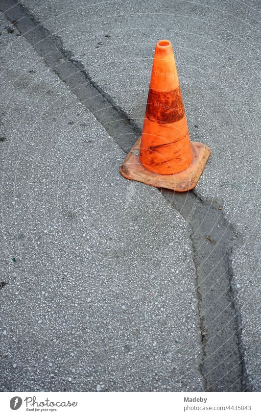 Altes Lübecker Hütchen in leuchtendem Orange auf einer ausgebesserten grauen Straßendecke in Adapazari in der Provinz Sakarya in der Türkei Kegel