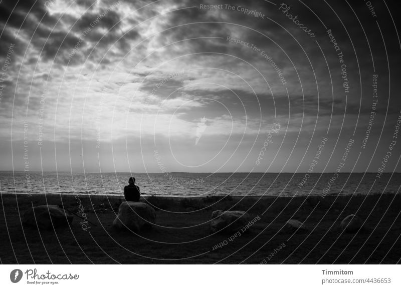 Ganz im Moment Nordsee Küste Wasser Wolken Himmel Frau sitzen Steine Gedanken Vergangenheit Zukunft jetzt Licht hell dunkel Sonne Dänemark schauen meditieren