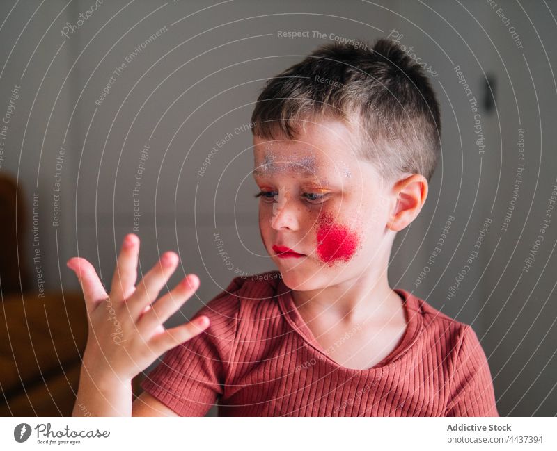 Schmutziger Junge mit Schminke auf den Wangen zu Hause unordentlich Kosmetik Make-up Schönheit dreckig Fokus Kindheit rote Lippen dekorativ achtsam freie Zeit