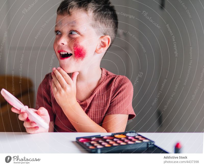 Schockierter Junge mit geschminktem Gesicht zu Hause Deckel Mund dreckig Kosmetik Make-up erstaunt sprachlos unglaublich heimwärts Erstaunen Spiegel Lidschatten