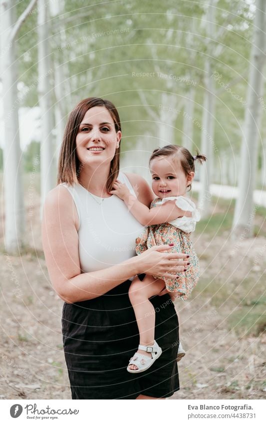 Porträt der schönen Mutter hält Baby Mädchen in Bäumen Weg. Familie, Spaß und Natur Konzept Wald Glück Kindheit Lächeln laufen Kaukasier Spanien Kleid