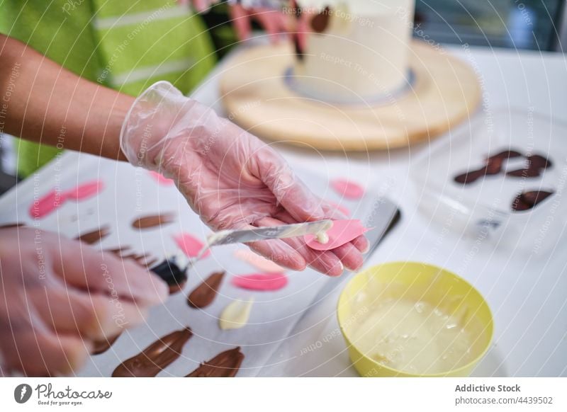 Konditorin bereitet Festtagskuchen mit bunter Schokolade vor Frau Sahne süß dekorieren Blütenblatt Dessert lecker Tisch Gebäck professionell Koch Feinschmecker