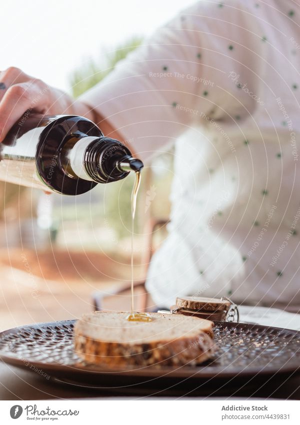 Erntehelfer gießt Sirup auf eine Scheibe Brot Person Frühstück eingießen Lebensmittel Terrasse Sommer hinzufügen süß geschmackvoll lecker frisch Tisch Ernährung