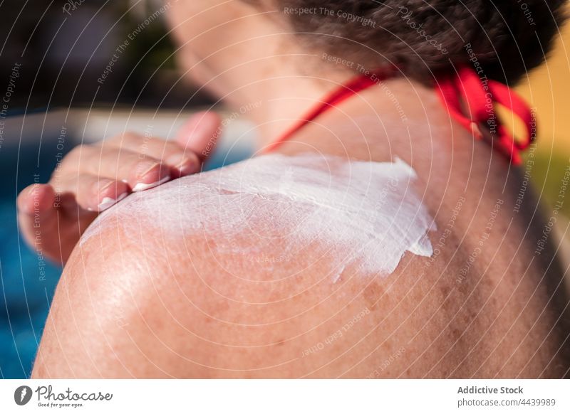 Anonyme alte Frau, die sich am Pool mit Lotion einschmiert Senior Sonnenbad Sonnencreme Sahne bewerben positiv Hydrat Kälte Beckenrand sorgenfrei Wasser