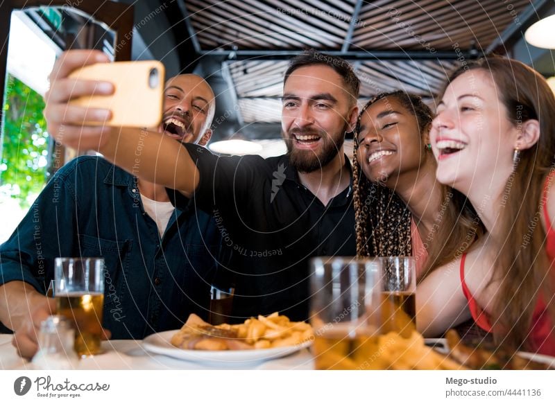 Eine Gruppe von Freunden macht ein Selfie mit einem Mobiltelefon in einem Restaurant. Zusammensein trinken Bier Mobile Telefon Lebensmittel Mahlzeit