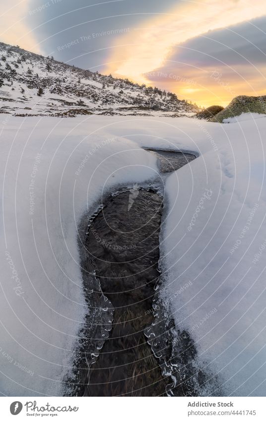 Fluss fließt durch verschneites Tal im Hochland unter buntem Himmel bei Sonnenuntergang Schnee Natur Umwelt spektakulär Winter Gelände Berge u. Gebirge kalt