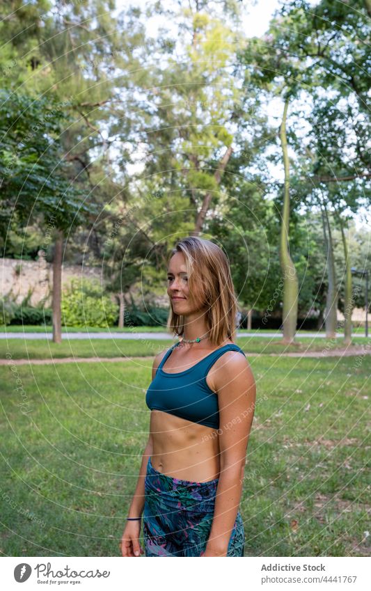 Sportlerin in Sportkleidung steht im Park und schaut weg Sportbekleidung Training sportlich Gesundheit positiv Energie Frau passen schlank Aktivität stehen üben