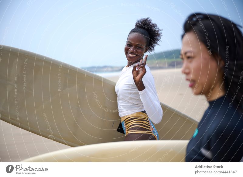 Diverse Surfer mit Surfbrettern im schäumenden Meer Sportlerinnen Surfen Longboard Zeit verbringen Körper schaumig Blauer Himmel Frauen Freundin Neoprenanzug