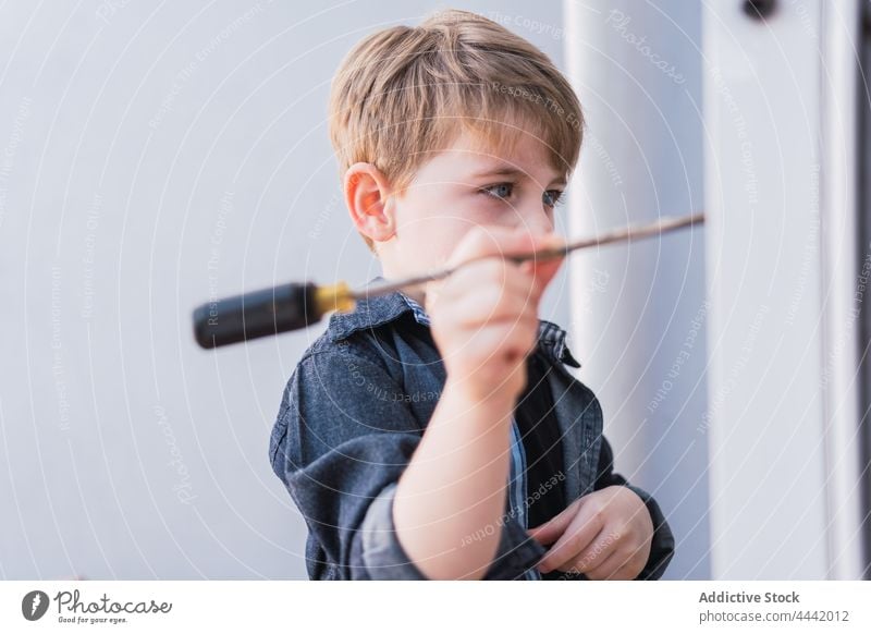 Aufmerksamer Junge mit Handschraubendreher am Fenster Schraubendreher manuell Werkzeug Fokus Kindheit Freizeit Instrument Reflexion & Spiegelung achtsam