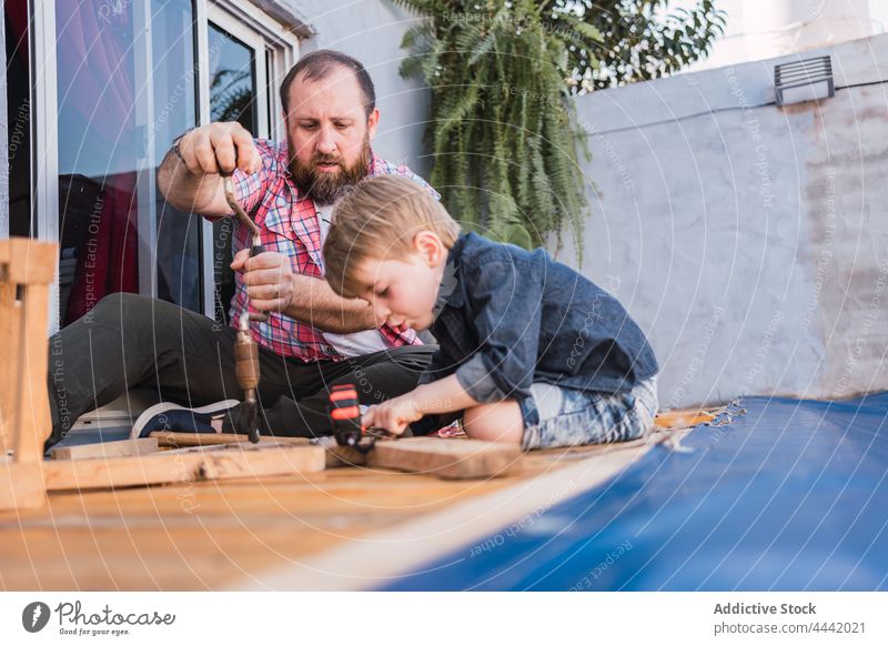 Vater erklärt dem Jungen, wie man mit Holz arbeitet Papa Sohn Holzarbeiten erklären zeigen Hammer Handarbeit diy Basteln achtsam Mann Zeit verbringen reden