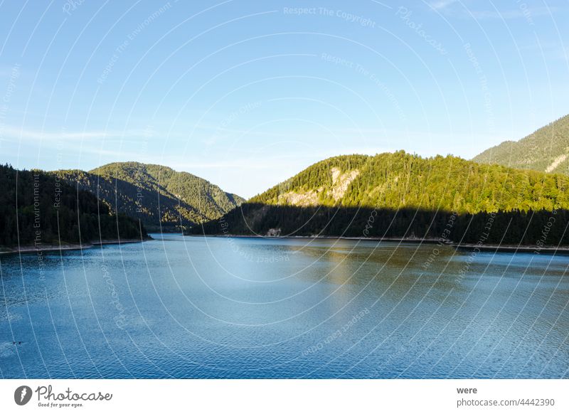 Blick über die Alpen und den Sylvenstein-Stausee an einem sonnigen Sommerabend Sonnenuntergang am See Hafengebiet Blauer Himmel Wolken Textfreiraum Abendsonne