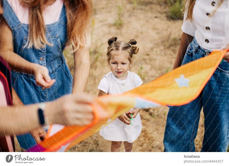 Nahaufnahme eines kleinen Mädchens, das seine Mutter dabei beobachtet, wie sie einen Drachen zum Start vorbereitet Milan Mama Baby Einführung von Kindheit