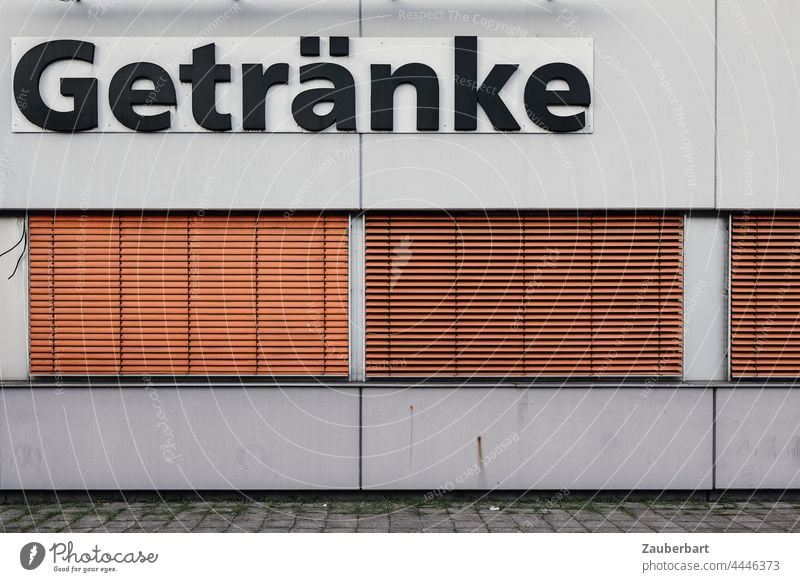 Getränke Aufschrift an Gebäude mit Betonwand mit orangen Jalousien geschlossen Wand Mauer Fassade Bauwerk grau trist geometrisch Architektur abstrakt