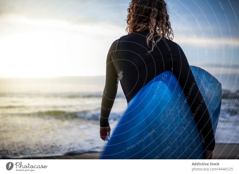 Frau steht am Ufer mit Surfbrett und schaut auf das Meer bei Sonnenuntergang Sonnenaufgang Neoprenanzug MEER Sportlerin Spaß nachdenken Wellen Brandung