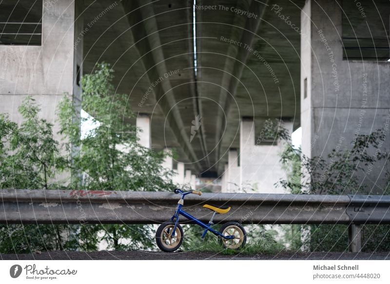 Altes Laufrad an einer Leitplanke unter einer Autobahnbrücke Kind Kindheit Außenaufnahme Bewegung Kleinkind Fahrrad Spielen früher vergangen Vergangenheit