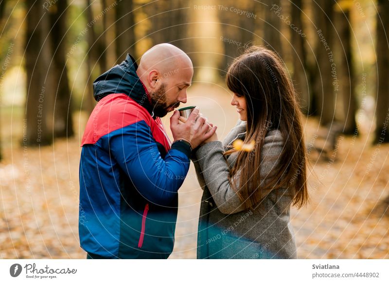 Ein Ehepaar bei einem heißen Getränk im herbstlichen Park. Das Konzept der Liebe und der Beziehungen Mann Frau Paar Herbst trinken Tee Thermoskanne romantisch