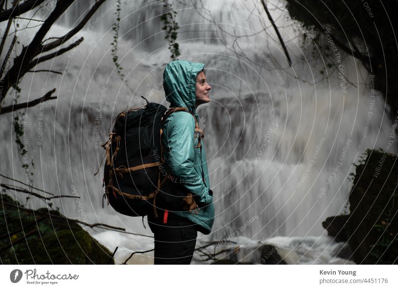 Mädchen vor einem Wasserfall Außenaufnahme Natur Farbfoto Fluss nass fließen Felsen Wald Rucksack natürlich