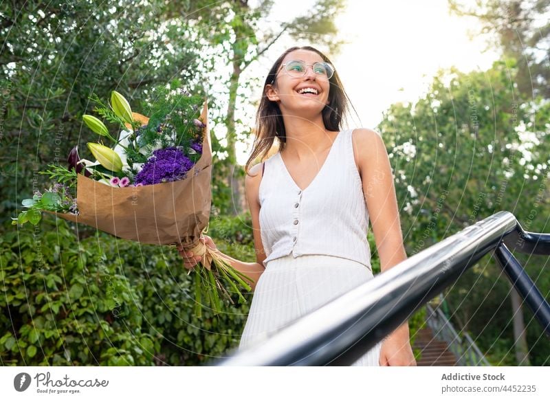 Fröhliche Frau mit Blumenstrauß in der Stadt Überraschung Geschenk Lächeln Brille Treppe heiter Inhalt charmant herzlich romantisch Blüte natürlich sortiert