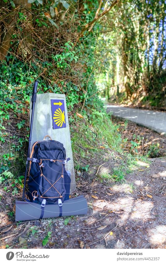 Meilenstein des Jakobswegs mit Rucksack und Wanderstock heiliger jakobusweg Kilometerstein Wegweiser Textfreiraum niemand aufrollbare Matte Panzer Straße reisen