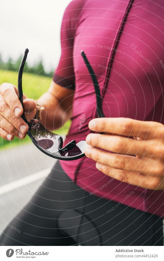 Crop-Fahrradfahrer mit Fahrrad-Sonnenbrille auf der Straße Radfahrer Fahrradfahren Sport kreativ Design behüten modern Stil Mann Sportbekleidung Training